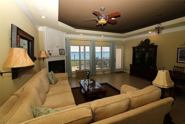17 Regency Pt, Conroe, TX 77356 - tiled living area featuring a ceiling fan, crown molding, a tray ceiling, recessed lighting, and a large fireplace