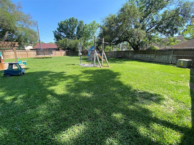 view of yard featuring a trampoline, a fenced backyard, and a playground