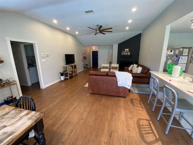 living room with ceiling fan, visible vents, vaulted ceiling, and wood finished floors