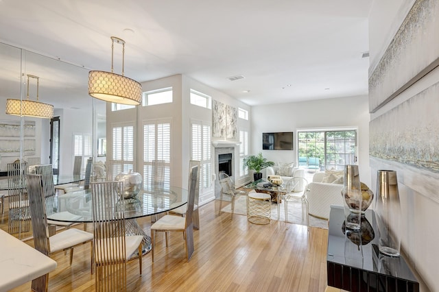 dining room with visible vents, light wood-type flooring, and a fireplace