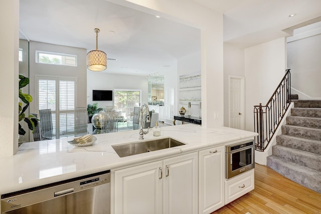 kitchen with open floor plan, a healthy amount of sunlight, stainless steel dishwasher, and a sink