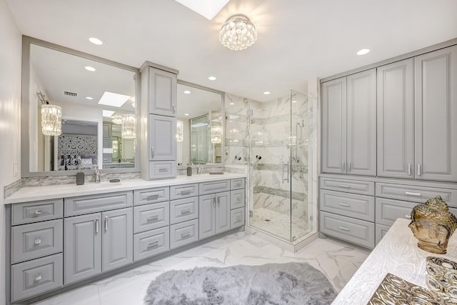 bathroom featuring a marble finish shower, recessed lighting, an inviting chandelier, and a sink