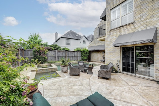 view of patio featuring a balcony, an outdoor living space, and a fenced backyard