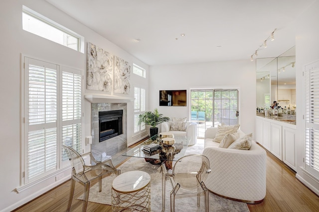 living room featuring a tile fireplace, rail lighting, and light wood-type flooring