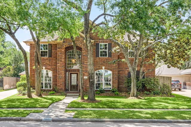 view of front of property with a front lawn, brick siding, and fence