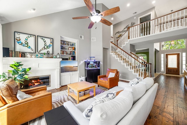 living area with high vaulted ceiling, visible vents, wood-type flooring, stairs, and ceiling fan