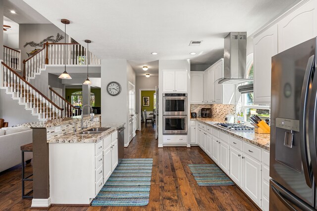 kitchen featuring a kitchen breakfast bar, stainless steel appliances, extractor fan, visible vents, and a sink
