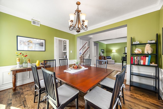 dining space with stairway, a notable chandelier, wood finished floors, ornamental molding, and visible vents