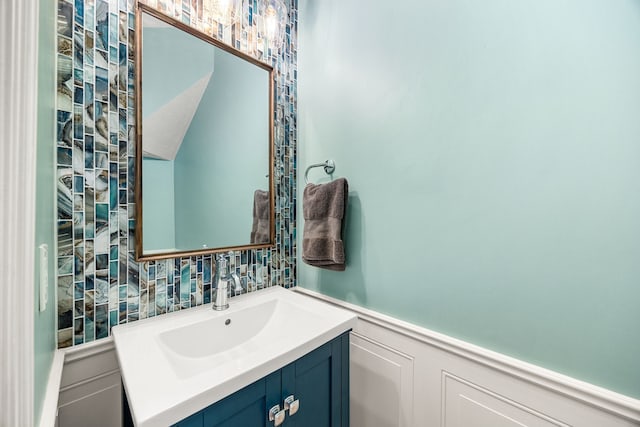 bathroom featuring a decorative wall, vanity, and wainscoting