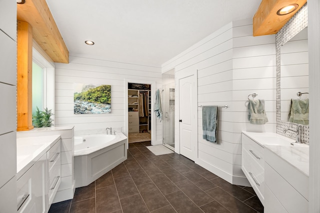 full bathroom featuring two vanities, a garden tub, wooden walls, and a sink