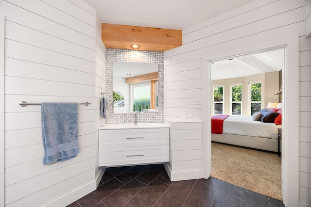 ensuite bathroom featuring a sink, wood walls, tile patterned floors, and ensuite bathroom