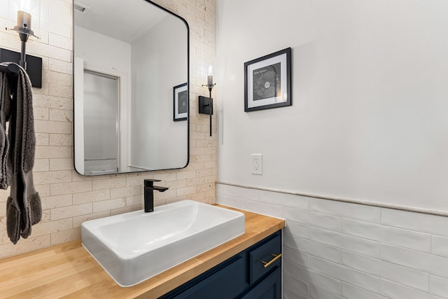 bathroom featuring tile walls, visible vents, vanity, and wainscoting