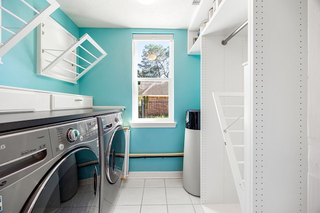 washroom with baseboards, washing machine and clothes dryer, laundry area, and light tile patterned floors