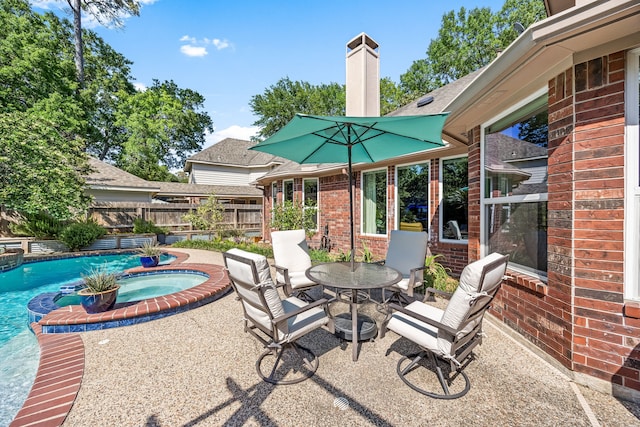 view of patio / terrace with fence, outdoor dining area, and a pool with connected hot tub