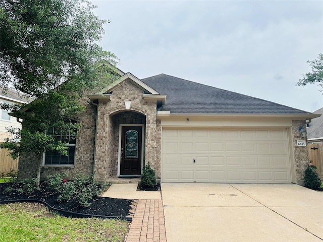 view of front facade featuring an attached garage, driveway, and roof with shingles