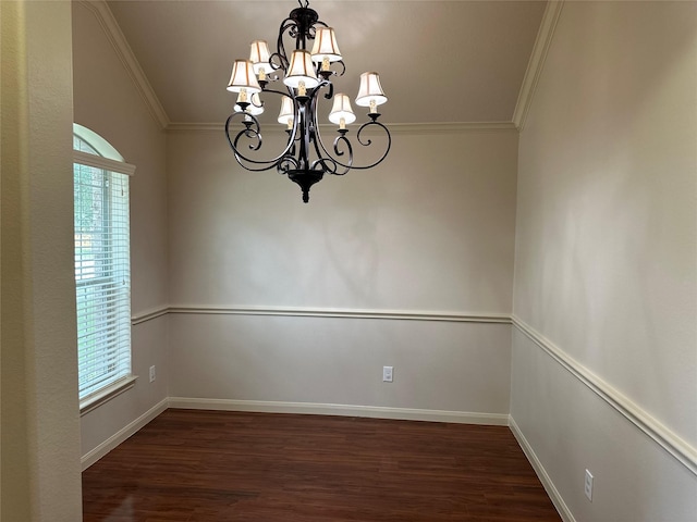 empty room with an inviting chandelier, ornamental molding, dark wood-style floors, and baseboards