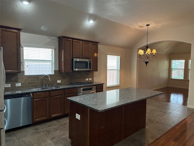 kitchen featuring tasteful backsplash, a sink, a healthy amount of sunlight, stainless steel appliances, and a notable chandelier
