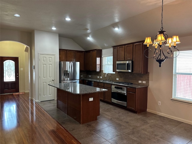 kitchen featuring stainless steel appliances, arched walkways, a sink, an inviting chandelier, and a kitchen island