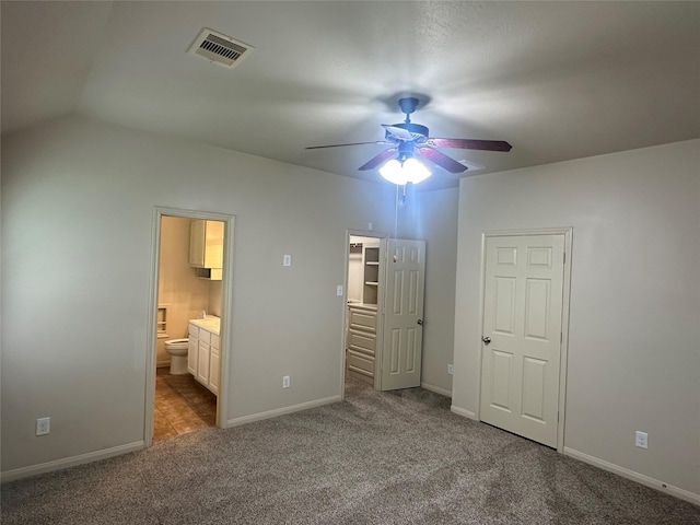 unfurnished bedroom featuring baseboards, ensuite bathroom, visible vents, and carpet