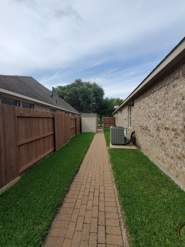 view of yard with a storage unit, an outbuilding, a fenced backyard, and central AC unit