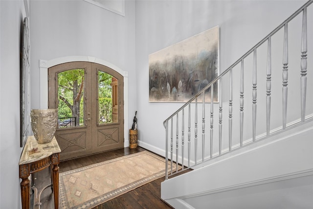 entrance foyer with baseboards, stairway, french doors, a high ceiling, and wood finished floors