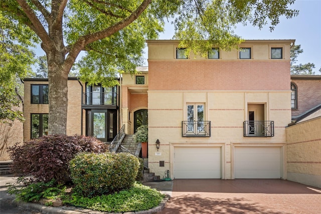 view of front of property with brick siding, a garage, decorative driveway, and a balcony