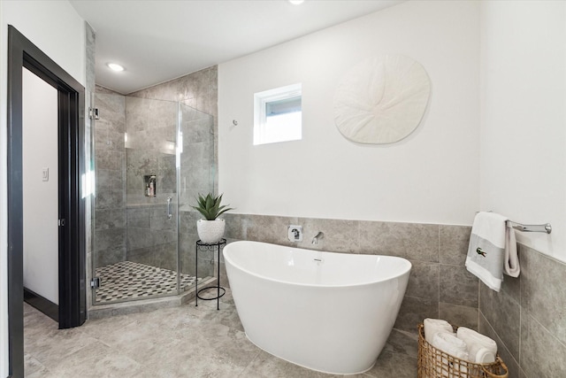 full bathroom featuring a freestanding tub, recessed lighting, a wainscoted wall, a shower stall, and tile walls