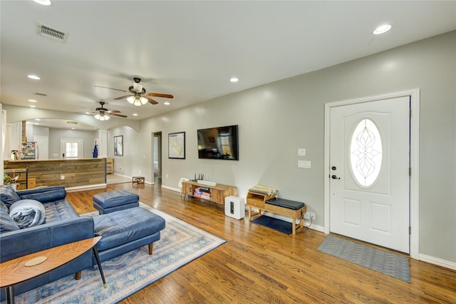 living room with arched walkways, wood finished floors, a ceiling fan, baseboards, and recessed lighting