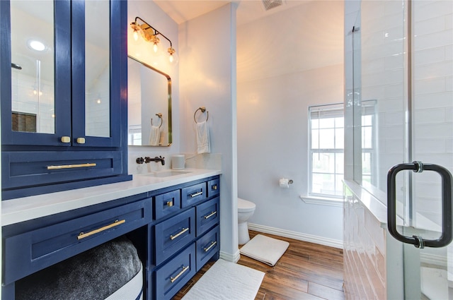 bathroom with baseboards, a shower stall, toilet, wood finished floors, and vanity