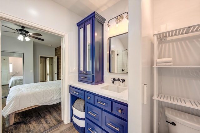 ensuite bathroom featuring wood finished floors, toilet, ceiling fan, and vanity