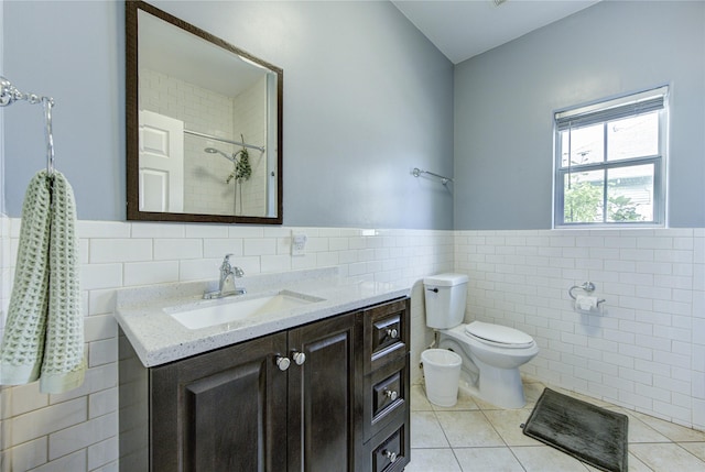 full bathroom featuring tile walls, tile patterned floors, wainscoting, toilet, and a tile shower