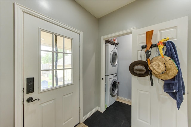 washroom featuring stacked washer / drying machine and baseboards