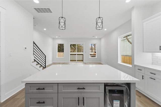 kitchen with light wood-type flooring, visible vents, gray cabinets, light countertops, and open floor plan