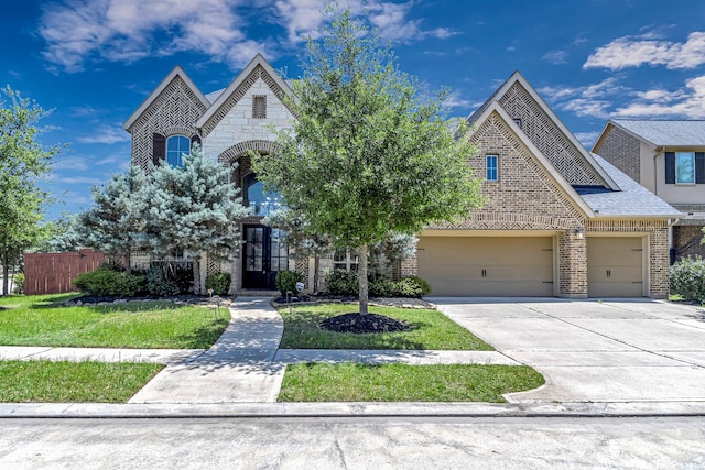 view of front of property featuring driveway, an attached garage, a front lawn, brick siding, and fence