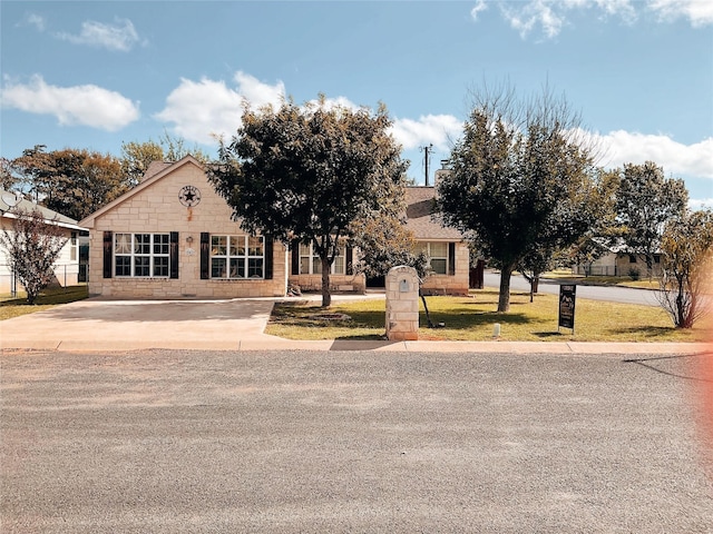 view of property hidden behind natural elements with stone siding and a front lawn