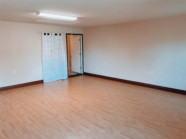 spare room with baseboards and light wood finished floors