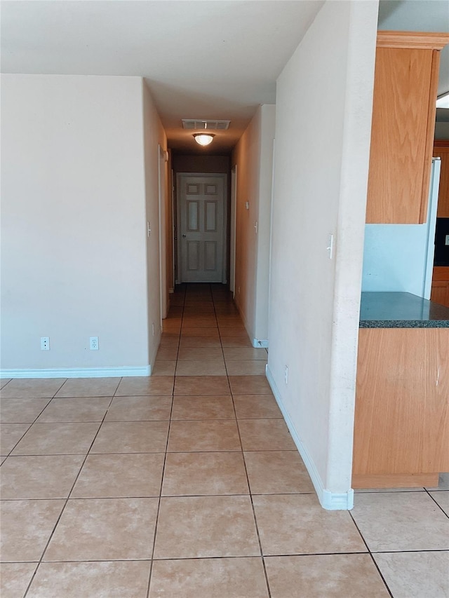 hall with visible vents, baseboards, and light tile patterned flooring
