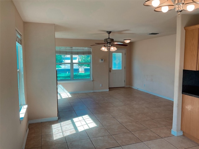 interior space with visible vents, baseboards, light tile patterned floors, and ceiling fan with notable chandelier