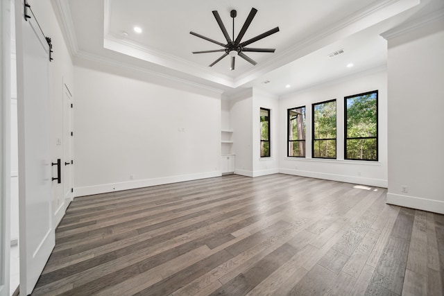 4458 Lily Bean, Montgomery, TX 77316 - unfurnished room with a barn door, dark wood finished floors, a raised ceiling, visible vents, and a ceiling fan