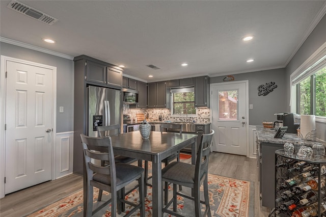 dining room with light wood-style flooring, ornamental molding, visible vents, and recessed lighting