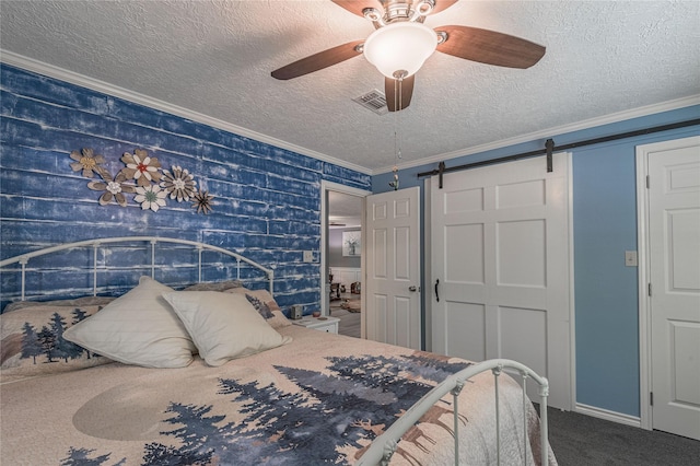 bedroom with visible vents, a barn door, a textured ceiling, crown molding, and carpet floors