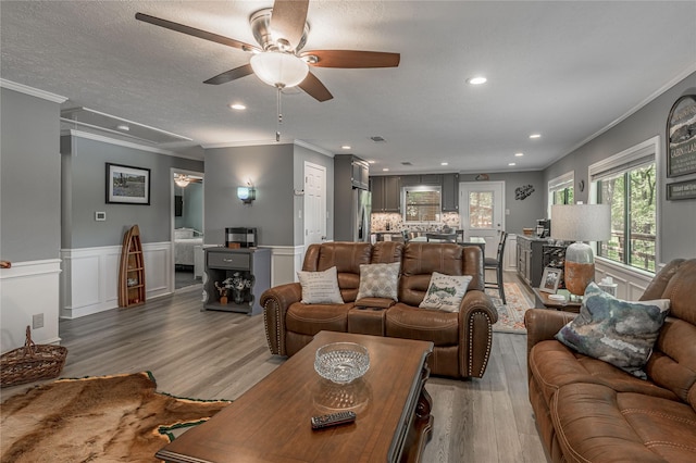 living area with recessed lighting, light wood finished floors, a ceiling fan, and crown molding