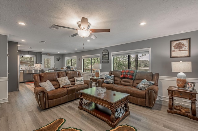 living room featuring light wood finished floors, a textured ceiling, and a ceiling fan