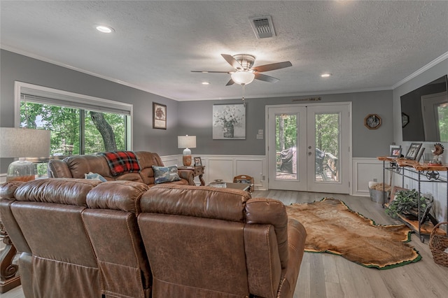 living room featuring ornamental molding, french doors, visible vents, ceiling fan, and wood finished floors