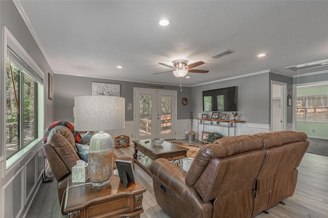 living room with ornamental molding, attic access, light wood-style floors, visible vents, and ceiling fan