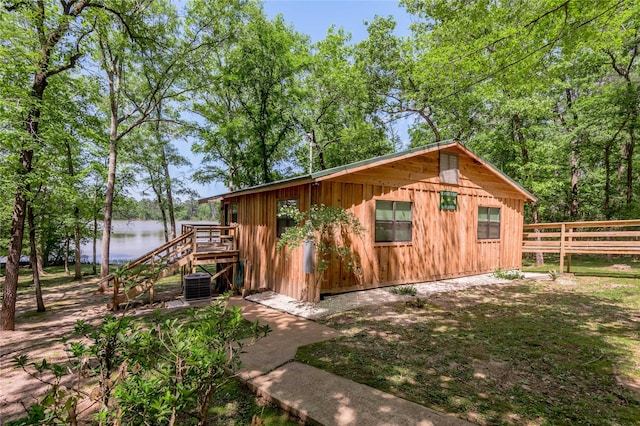 view of outbuilding with a water view, stairs, central AC, and fence