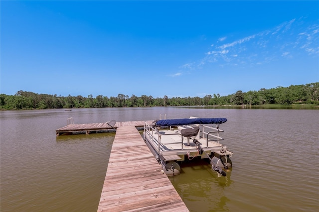view of dock with a wooded view and a water view