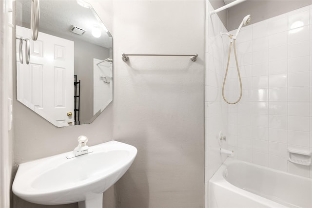 bathroom featuring shower / bathing tub combination, visible vents, and a sink