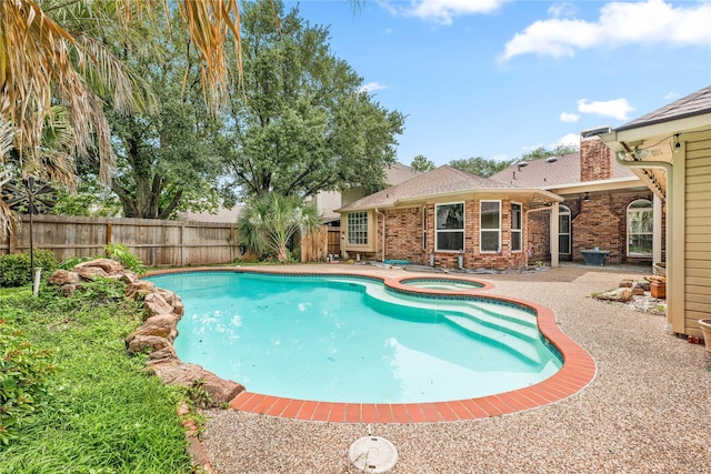 view of swimming pool featuring a patio, a pool with connected hot tub, and a fenced backyard