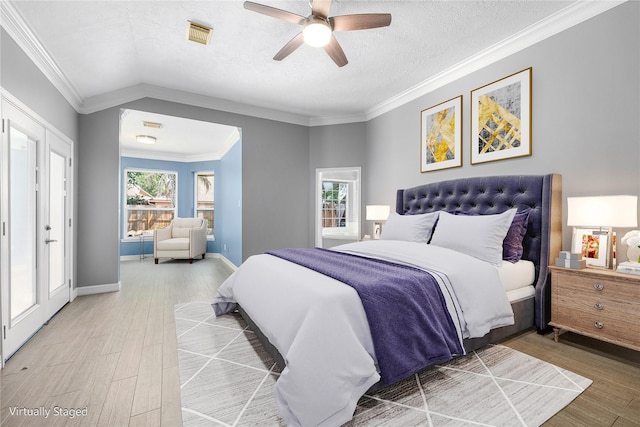 bedroom with a textured ceiling, visible vents, wood finished floors, and a ceiling fan
